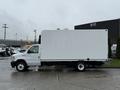 A white 2024 Ford E-450 box truck with a flatbed and closed cargo area on the back parked on a wet surface
