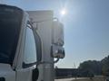 A 2012 Hino 338 truck with a shiny side mirror reflecting sunlight