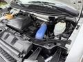 A 2013 Chevrolet Express engine compartment showcasing the engine block air intake and various components like hoses and fluid reservoirs