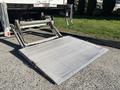 A metallic loading ramp extended from the rear of a truck with a textured surface for improved grip
