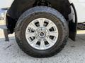 A close-up of a silver wheel from a 2020 Ford F-350 SD featuring a large tire with an aggressive tread pattern and a polished rim with multiple spokes