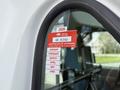 A 2002 Ford Econoline with a red certification sticker on the driver's side window displaying approval information and expiration dates for various months