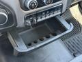 The interior of a 2020 Ram 2500 featuring a storage area with several slots for items and various control buttons above it