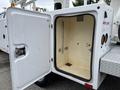 A white door of a utility box is open revealing an interior with a smooth surface and mounting points but no visible items inside