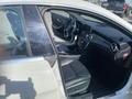 Interior view of a 2014 Mercedes-Benz CLA-Class featuring a black leather seat and steering wheel with various controls and dashboard elements visible