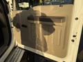 A beige interior door panel of a 2010 Ford F-550 featuring a handle and grooves for grip in a light shadow