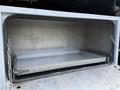 A metal storage compartment with an open sliding door revealing a flat interior tray inside a Sterling LT9500 truck