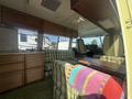 Interior of a 1976 GMC Motorhome featuring green plaid seating, a wooden table, cabinetry, and a cozy atmosphere