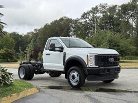 A white 2023 Ford F-450 SD chassis cab with a solid front design and large tires standing on a paved surface