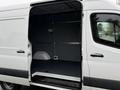 A white 2023 Mercedes-Benz Sprinter van with an open sliding door revealing a spacious interior designed for cargo transport
