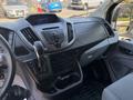 Interior view of a 2016 Ford Transit 150 focusing on the dashboard and gear shifter with various control buttons and cup holders