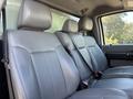 Interior view of a 2011 Ford F-550 showing gray leather seats in a row with seat belts fastened