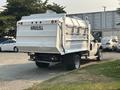 A 2009 Ford F-550 with a white cargo body that has a marked HAU-ALL sign on the rear and a flatbed design suitable for heavy-duty transport