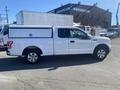 A white 2017 Ford F-150 pickup truck with a fitted cap in the bed parked on a lot