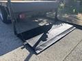 A black diamond plate loading ramp attached to the back of a truck with a sturdy chain holding it in place