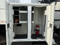 Open doors of a 2011 International 4300 revealing empty storage compartments and a fire extinguisher on the right
