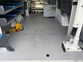 Interior of a 2023 Ford Transit with shelving units on one side and a clear floor space for cargo or equipment storage