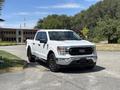 A white 2021 Ford F-150 pickup truck with black wheels parked on a paved surface