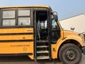A yellow 2007 Freightliner B2 school bus with an open door and stairs visible, showing seating and driver area inside