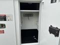 A 2013 Freightliner 114SD truck with a partially open storage compartment revealing shelves and hooks inside
