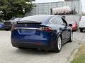 A blue 2020 Tesla Model X viewed from the rear showing sleek lines and a rear spoiler with distinctive taillights