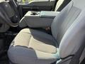 A gray fabric driver's seat of a 2015 Ford F-550 with an armrest and a textured pattern on the seat cushion