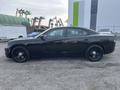 A black 2015 Dodge Charger parked with a sleek profile showcasing its smooth lines and distinctive design