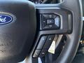 Close-up of the steering wheel of a 2020 Ford F-350 SD featuring volume control buttons and a voice command button