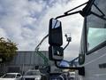 A 2012 International DuraStar 4300 truck with a large side mirror reflecting its surroundings