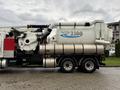 A 2014 International 7500 vacuum truck with a large cylindrical tank and connected hoses designed for suctioning debris and waste