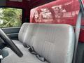 Interior view of a 2002 GMC C7500 showing a gray bench seat with seatbelts and a steering wheel in the foreground