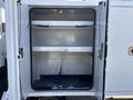 An open storage compartment of a 2019 Freightliner M2 106 with two shelves and a chain on the bottom