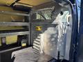 Interior view of a 2016 Ford Transit 150 cargo van featuring metal shelving a partition and tool storage compartments