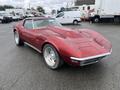 A 1970 Chevrolet Corvette in a deep red color featuring a long hood and a convertible top with prominent fenders and a sleek body design