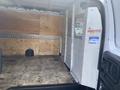 Interior of a 2022 GMC Savana cargo van featuring wooden floor and a partition with a metal grid divider