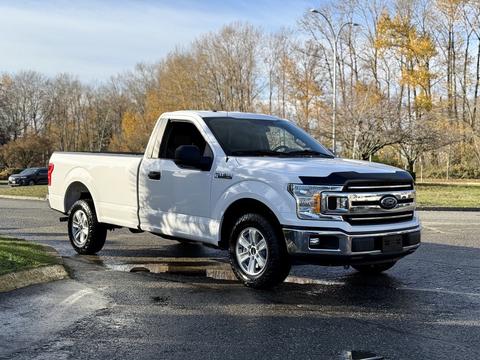 A white 2018 Ford F-150 pickup truck parked with a single cab and chrome grille featuring alloy wheels and a chrome bumper