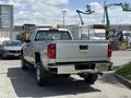 A silver 2016 Chevrolet Silverado 2500HD pickup truck with a chrome tailgate and the Chevrolet emblem is parked with its rear facing forward