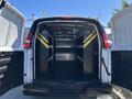 A 2019 GMC Savana van with its rear doors open revealing a spacious interior outfitted with black shelving units featuring yellow stripes