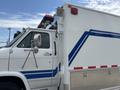 A white 1994 GMC Vandura 3500 with blue stripes features a side view mirror and an emergency light mounted on the roof