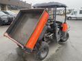 A 2010 Kubota RTV 900 utility vehicle with a raised dump bed and rugged tires in a parking lot setting