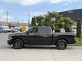 A 2018 RAM 1500 in black parked at an angle showcasing its crew cab design and stylish alloy wheels