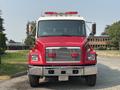 A red 1999 Freightliner FL80 fire truck with a white cab and multiple lights on the roof facing forward