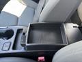 A black plastic console tray with a textured surface located between two gray front seats of a car