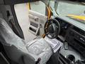 A 2021 Ford Econoline interior showcasing the driver's seat covered in plastic a steering wheel and dashboard with various controls and gauges visible