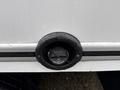 A black circular fuel filler cap with a hinged cover attached to the side of a 2024 Ford E-450 van