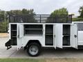 A white 2020 Ford F-550 with an open utility bed featuring multiple doors and shelves for storage