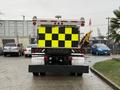 A 2016 Freightliner 108SD truck with a bright yellow and black checkered rear display and an attached equipment arm