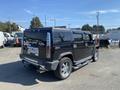 A black 2003 Hummer H2 with chrome details and oversized wheels parked in an outdoor lot