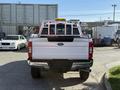 A white 2021 Ford F-250 Super Duty truck with a ladder rack on the bed is shown from the rear