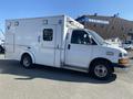 A white 2011 Chevrolet Express converted into an ambulance with a boxy rear and emergency lights on top